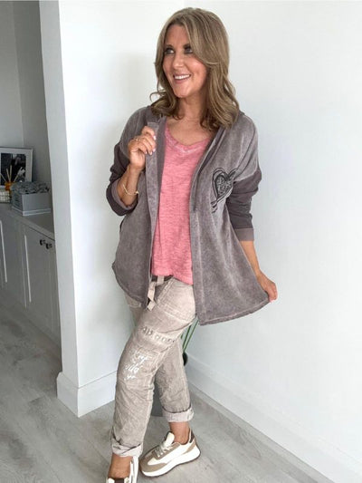 Woman wearing a velour zip-up hoodie jacket with pockets and embroidered detail, styled with matching joggers and a white top.