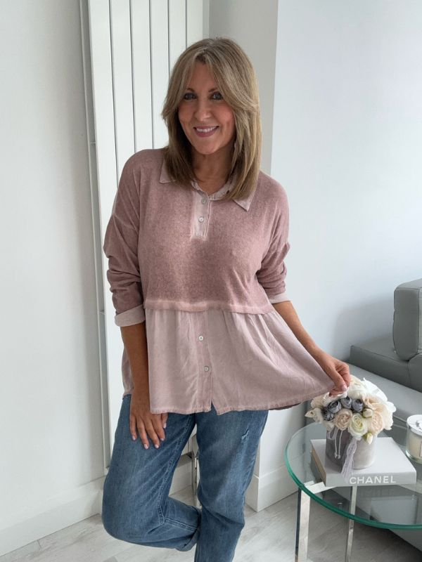Woman wearing a vintage rose two-tone blouse with button details, paired with blue jeans and gold pointed flats, standing indoors by a round glass table and a flower arrangement.