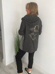 Woman wearing a velour zip-up hoodie jacket with pockets and embroidered detail, styled with matching joggers and a white top.