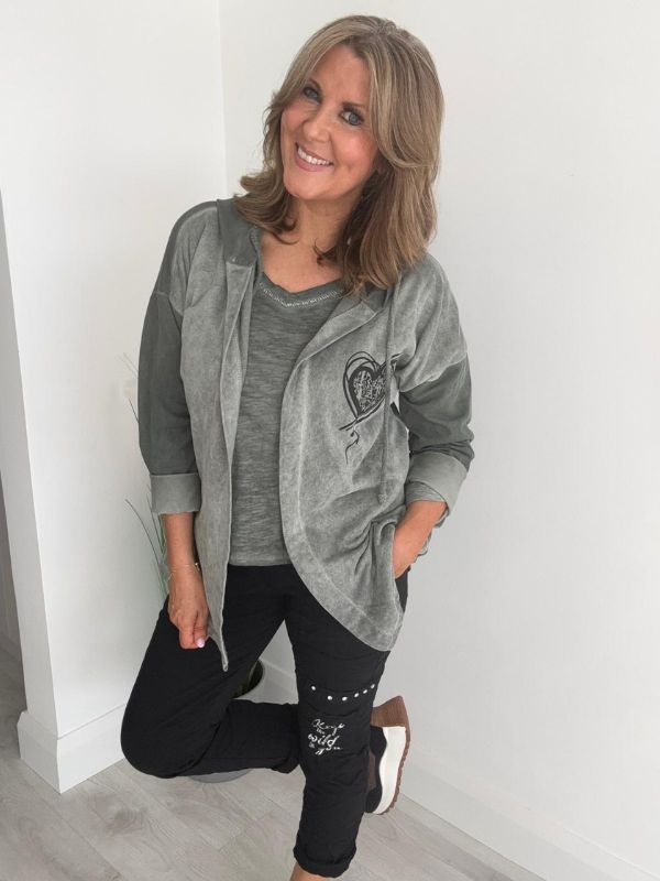 Woman wearing a velour zip-up hoodie jacket with pockets and embroidered detail, styled with matching joggers and a white top.