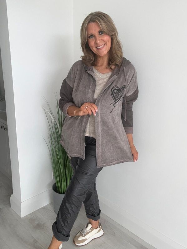 Woman wearing a velour zip-up hoodie jacket with pockets and embroidered detail, styled with matching joggers and a white top.