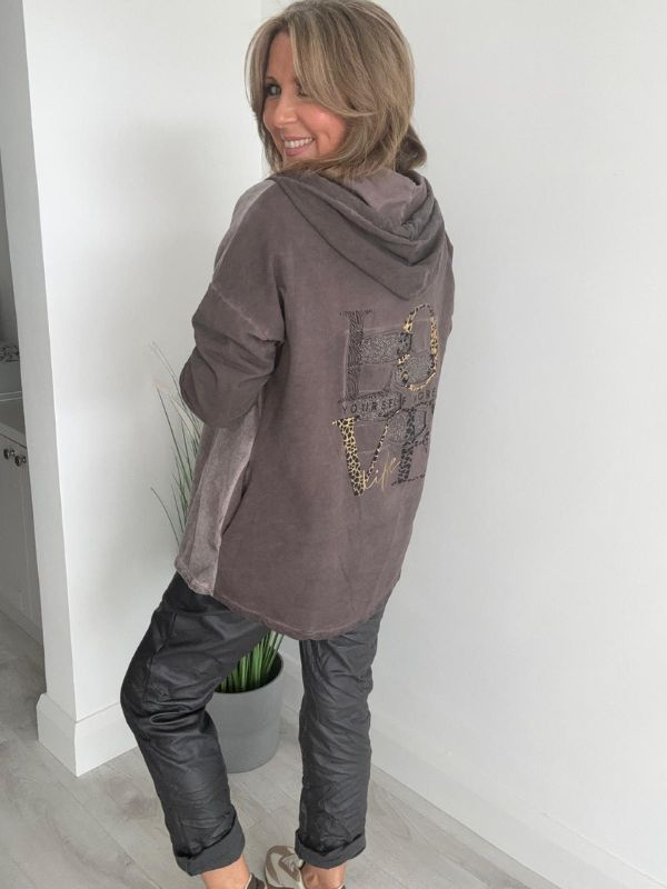 Woman wearing a velour zip-up hoodie jacket with pockets and embroidered detail, styled with matching joggers and a white top.