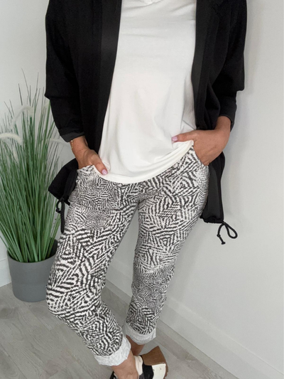Person wearing black and white patterned pants with a plain background