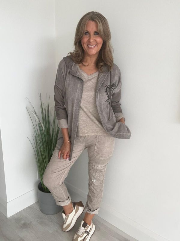 Woman wearing a velour zip-up hoodie jacket with pockets and embroidered detail, styled with matching joggers and a white top.