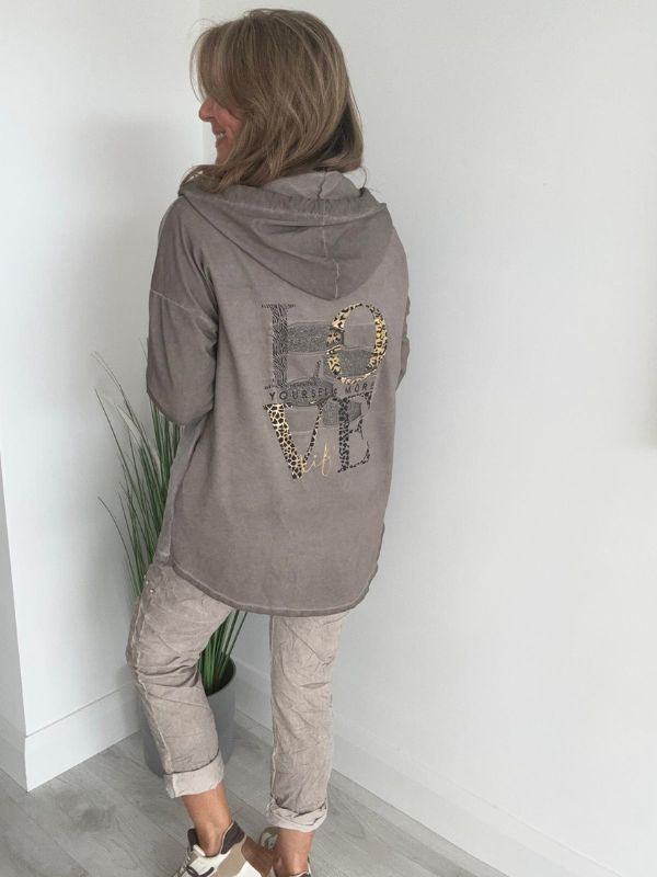 Woman wearing a velour zip-up hoodie jacket with pockets and embroidered detail, styled with matching joggers and a white top.
