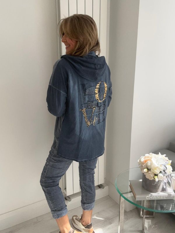 Woman wearing a velour zip-up hoodie jacket with pockets and embroidered detail, styled with matching joggers and a white top.