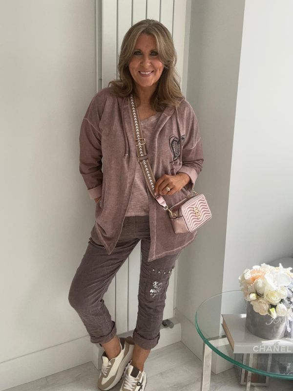 Woman wearing a velour zip-up hoodie jacket with pockets and embroidered detail, styled with matching joggers and a white top.