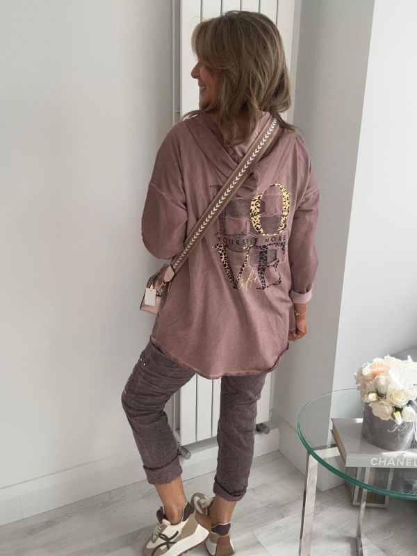 Woman wearing a velour zip-up hoodie jacket with pockets and embroidered detail, styled with matching joggers and a white top.
