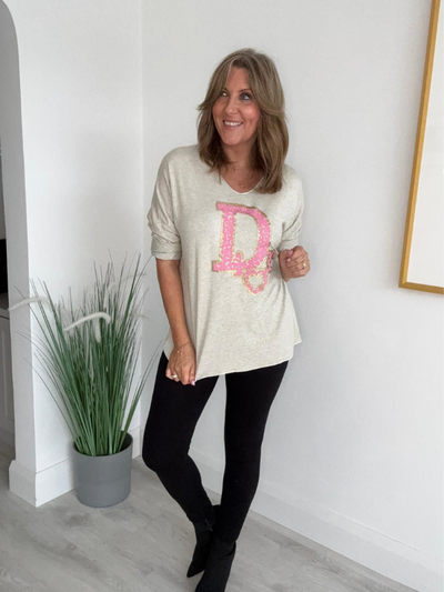 Individual standing indoors, wearing a long-sleeve top and leggings.