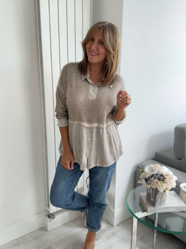 Woman wearing a vintage rose two-tone blouse with button details, paired with blue jeans and gold pointed flats, standing indoors by a round glass table and a flower arrangement.