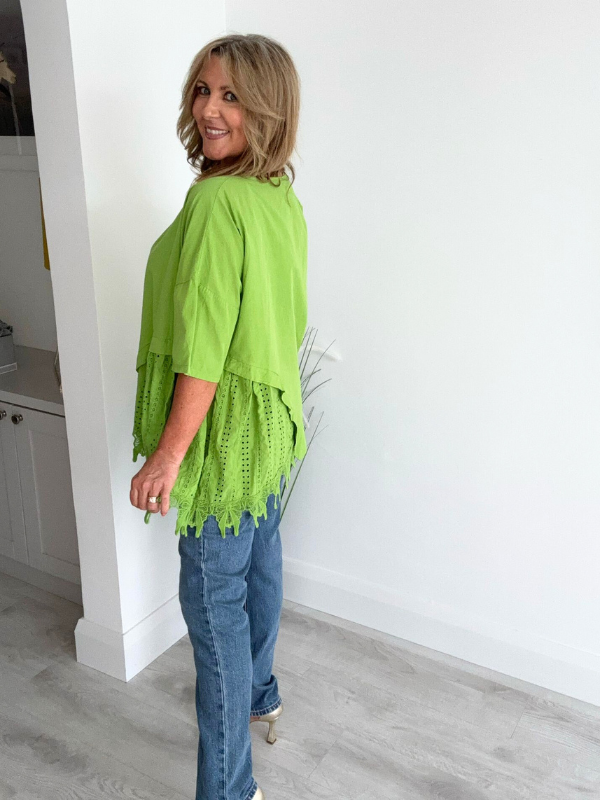 Woman wearing an asymmetric cotton top with lace side detail, styled with jeans and heels
