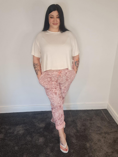 Woman wearing plus size printed joggers in pink with floral pattern – one size fits 16 to 24