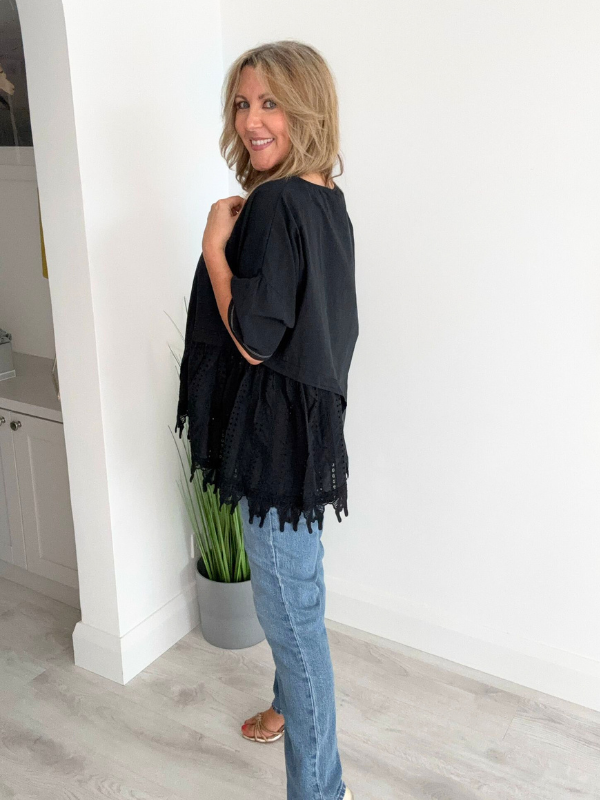 Woman wearing an asymmetric cotton top with lace side detail, styled with jeans and heels