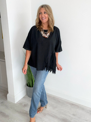 Woman wearing an asymmetric cotton top with lace side detail, styled with jeans and heels