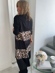 Woman wearing a black and animal print dress standing in front of a mirror.