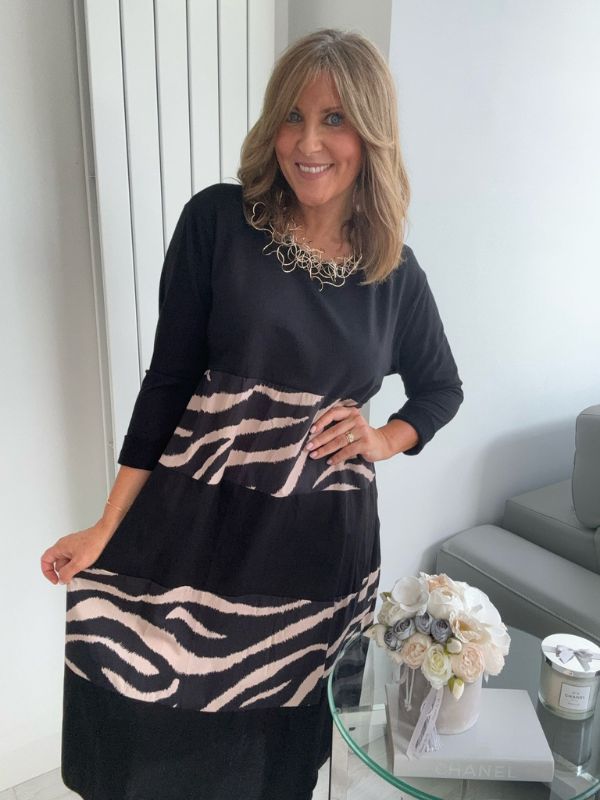 Woman wearing a black dress with zebra pattern in an indoor setting