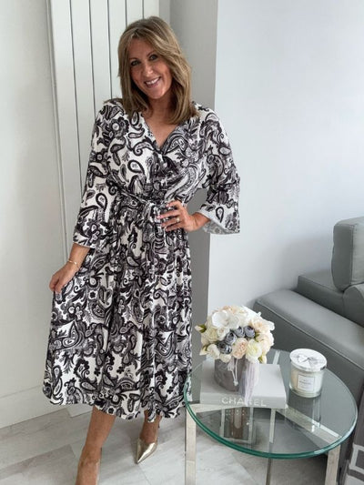 Woman wearing a black and white patterned dress in a modern living room.