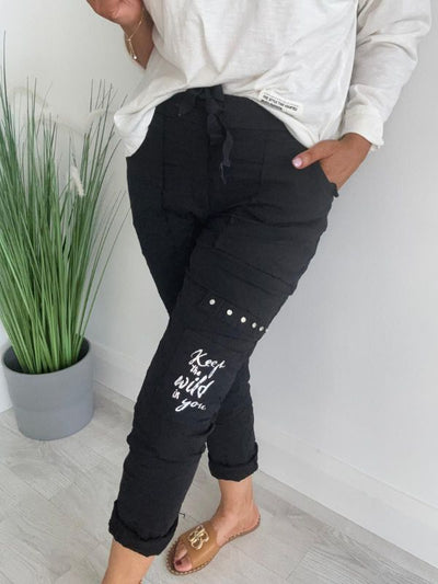 Women’s “Keep the Wild in You” cargo joggers with elastic tie waist, stud embellishments, printed motivational quote, and multiple pockets.
