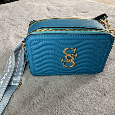 Textured 2-zip crossbody bag with adjustable patterned strap, gold-tone hardware, and two spacious compartments, available in black, red, gold, tan, rose gold, cream, pink, and blue.