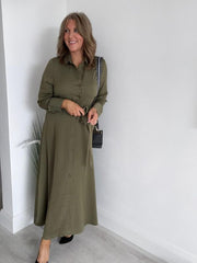 Woman wearing a khaki green button-down belted maxi shirt dress with long sleeves.