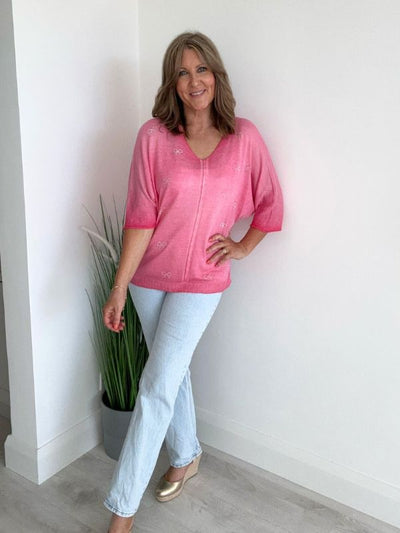 Model wearing a lightweight V-neck jumper in soft knit, featuring front seam detail and relaxed fit. Available in multiple colors and fits UK sizes 8 to 18."
