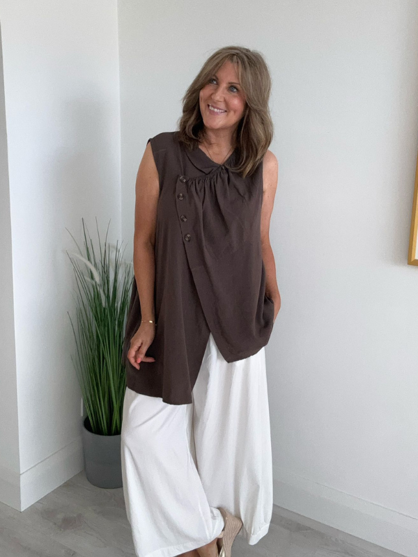 Model wearing asymmetric buttoned sleeveless vest top – relaxed fit and draped silhouette