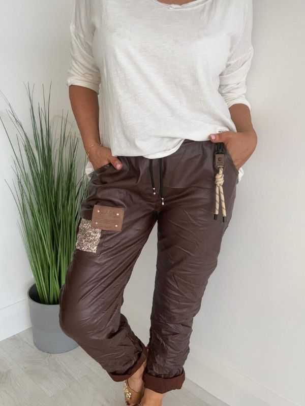 Women’s leatherette joggers in faux leather with soft fleece lining, elastic waistband, adjustable drawstring, side pockets, and patch detail. 