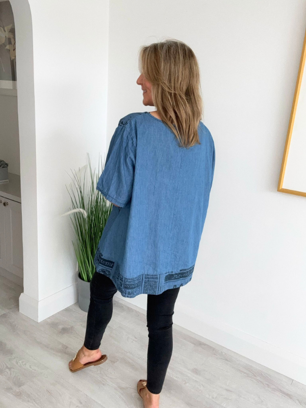 Vintage oversized denim blouse with abstract newspaper print on sleeves, round neckline, and high-low hem – 100% cotton, free size 8–20