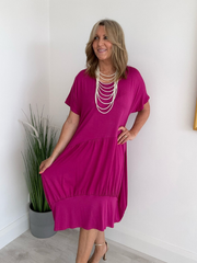 Model wearing a relaxed fit tunic dress with an asymmetric tiered hem, short sleeves, and round neckline, styled for casual comfort and everyday elegance