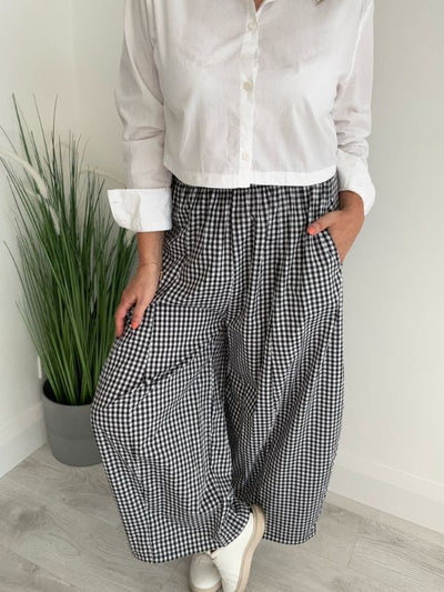 Woman wearing wide-leg gingham trousers with side pockets, paired with a cropped white button-down shirt