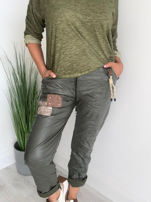 Women’s leatherette joggers in faux leather with soft fleece lining, elastic waistband, adjustable drawstring, side pockets, and patch detail. 