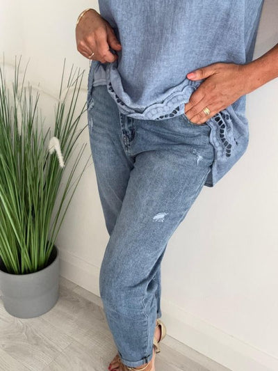 Light blue Melly mom jeans with high-waist fit, light distressing, rolled hem, and classic 5-pocket design, displayed folded on a neutral background.
