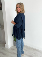 Woman wearing an asymmetric cotton top with lace side detail, styled with jeans and heels