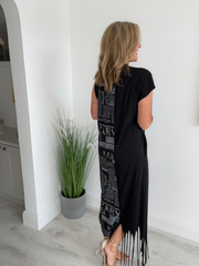 Model wearing a black dress with grey newspaper print panel, drawstring detail, and side pockets, styled for a bold and modern streetwear-inspired look