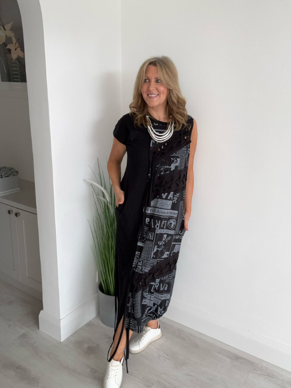 Model wearing a black dress with grey newspaper print panel, drawstring detail, and side pockets, styled for a bold and modern streetwear-inspired look