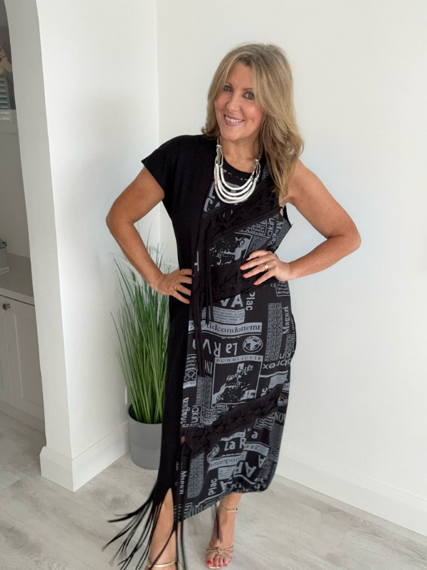 Model wearing a black dress with grey newspaper print panel, drawstring detail, and side pockets, styled for a bold and modern streetwear-inspired look