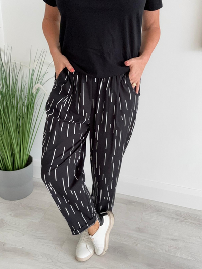 Model wearing wide-leg dash print trousers with elastic waistband and side pockets, styled for a relaxed yet modern look