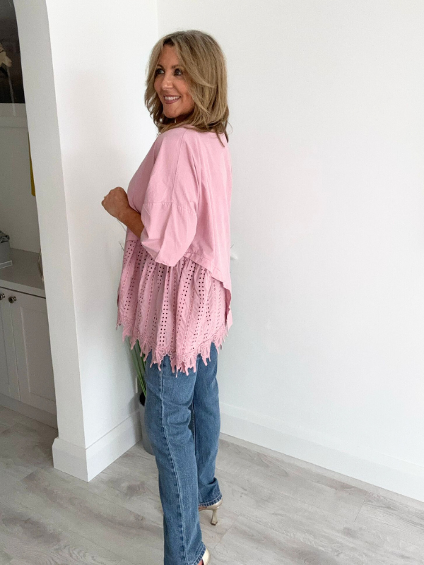 Woman wearing an asymmetric cotton top with lace side detail, styled with jeans and heels