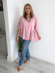 Woman wearing an asymmetric cotton top with lace side detail, styled with jeans and heels