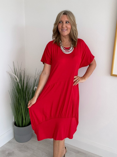 Model wearing a relaxed fit tunic dress with an asymmetric tiered hem, short sleeves, and round neckline, styled for casual comfort and everyday elegance
