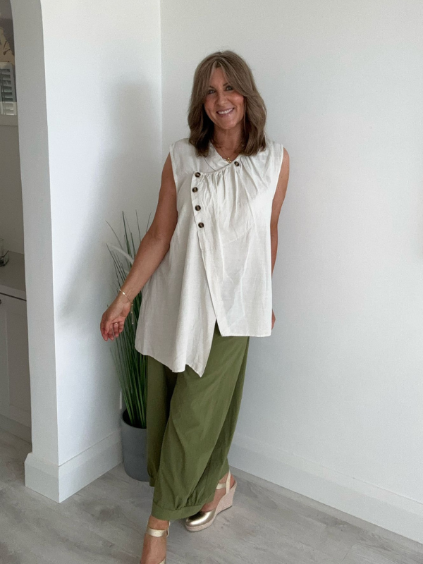 Model wearing asymmetric buttoned sleeveless vest top – relaxed fit and draped silhouette
