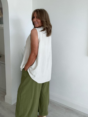 Model wearing asymmetric buttoned sleeveless vest top – relaxed fit and draped silhouette