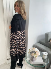 Woman wearing a black and beige patterned dress in a modern living room.
