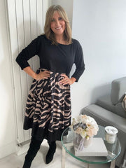 Woman wearing a black and beige patterned dress in a modern living room.